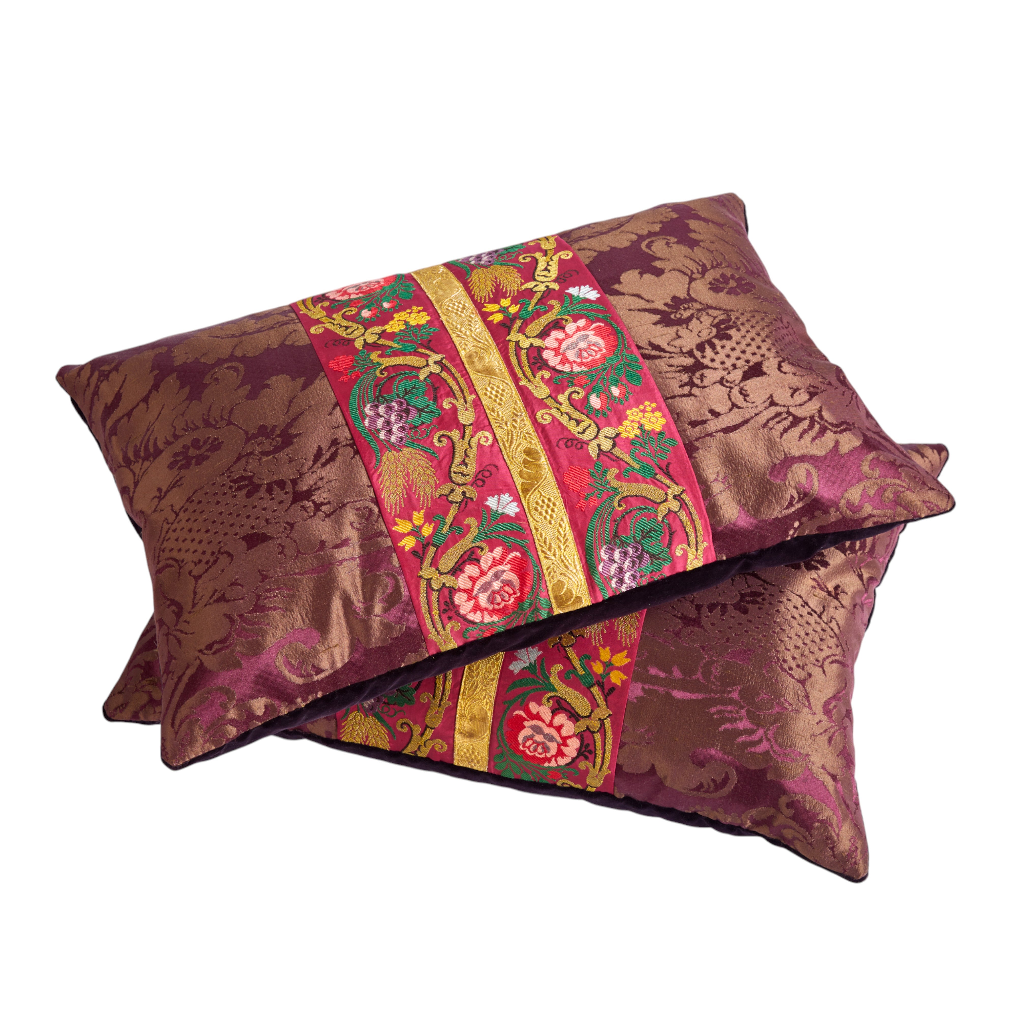 A pair of aubergine silk damask cushions with a central 19th Century embroidered trim