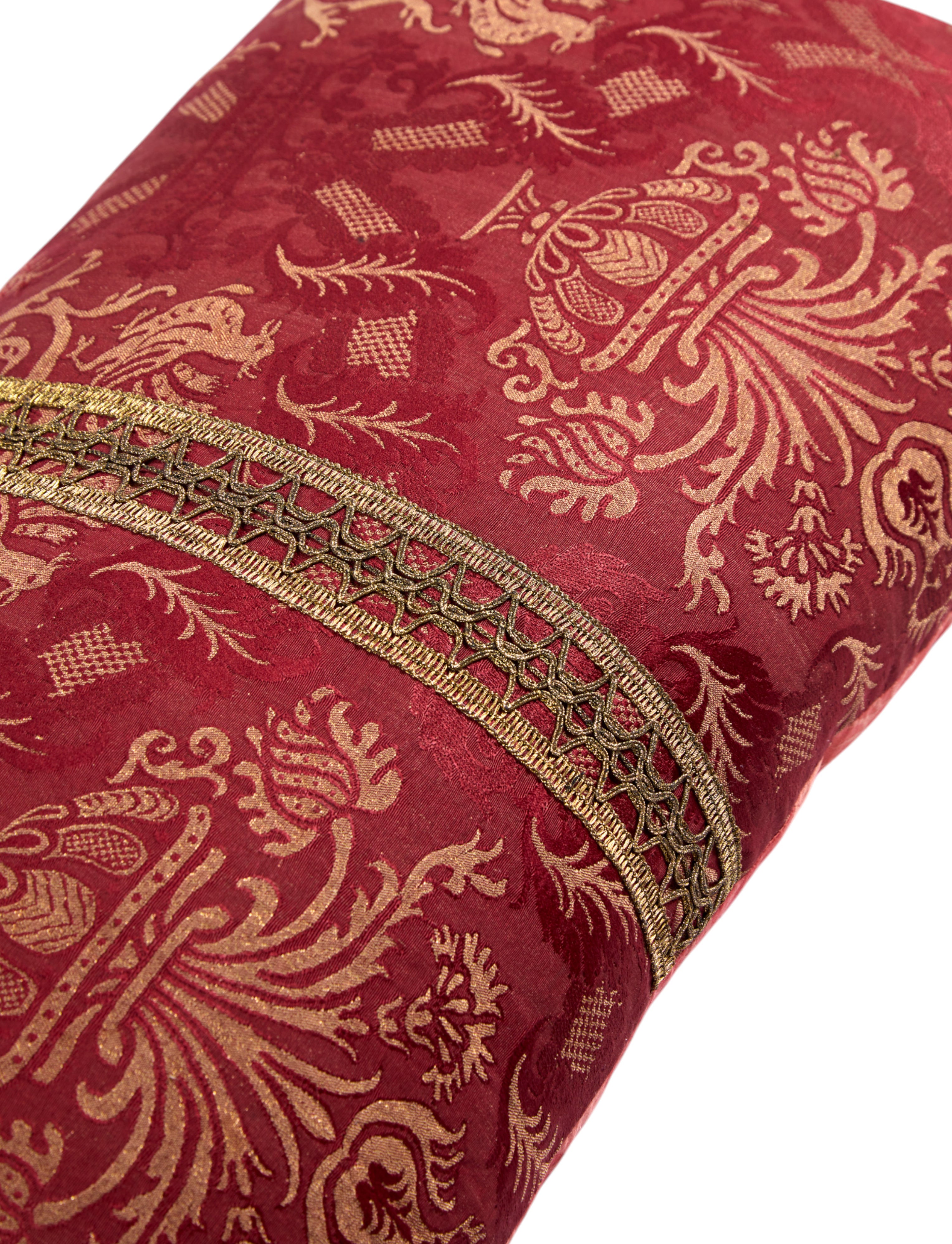 A Claret Bolster Cushion made from antique woven damask with an 18th Century trim