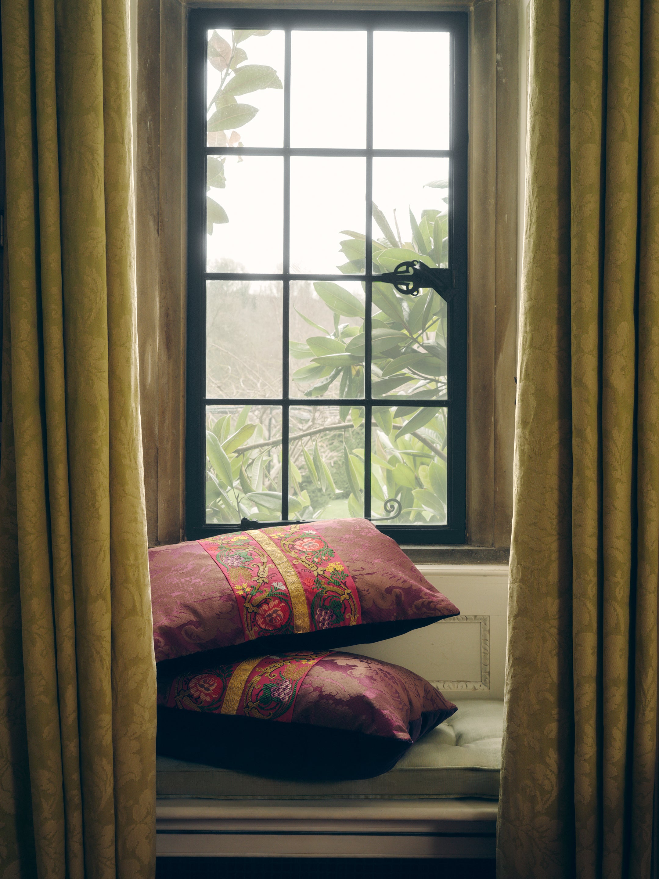 A pair of aubergine silk damask cushions with a central 19th Century embroidered trim