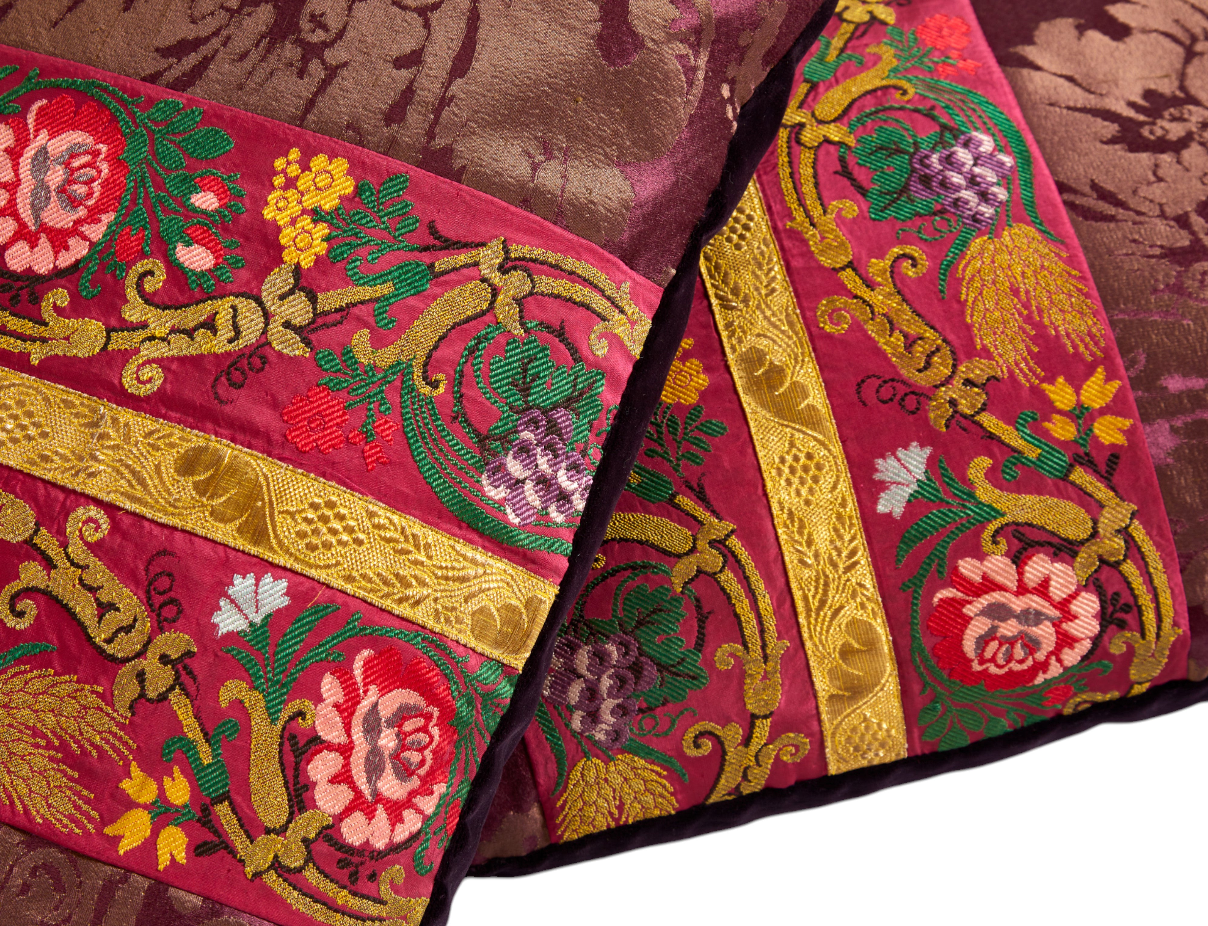 A pair of aubergine silk damask cushions with a central 19th Century embroidered trim