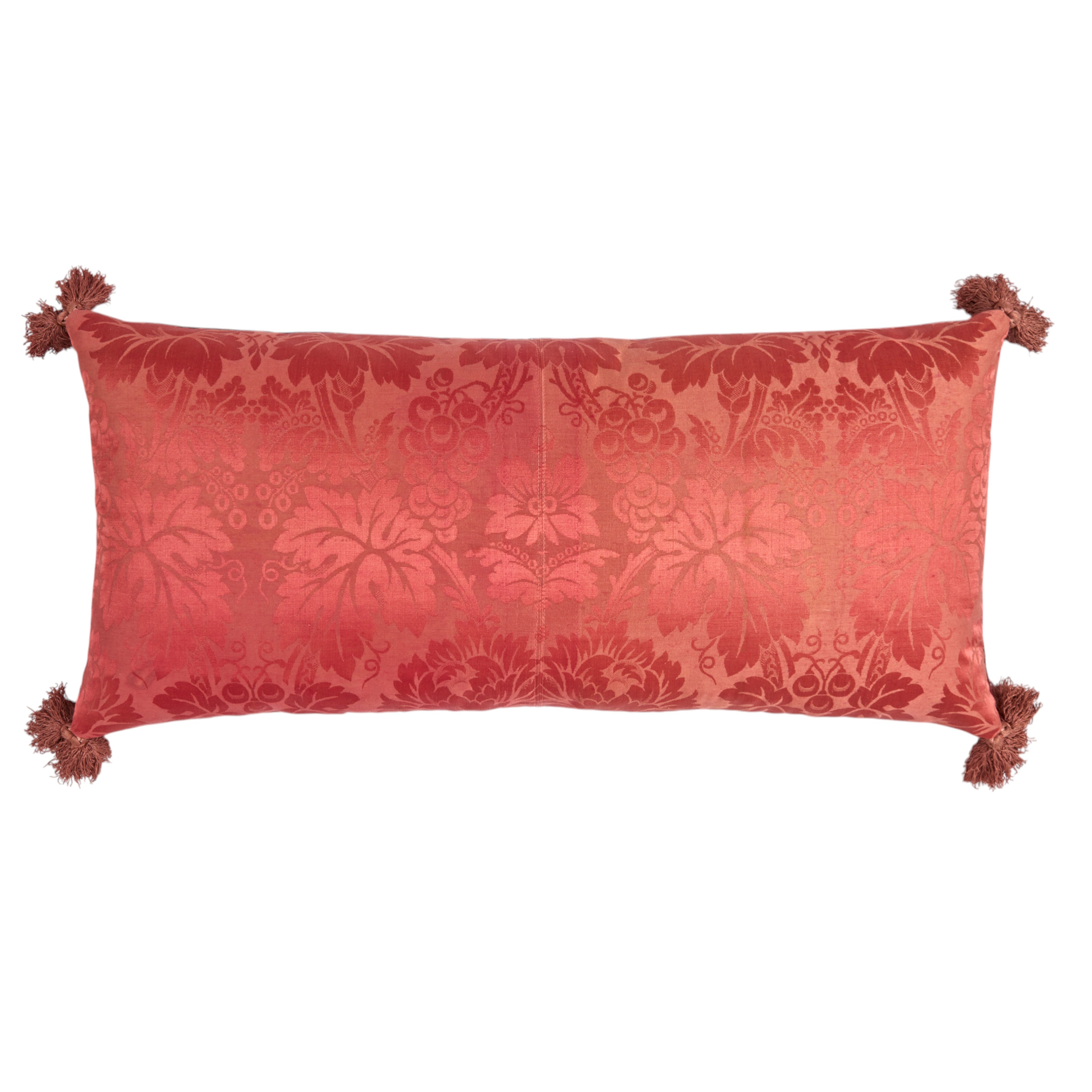 A Claret Bolster Cushion made from antique woven damask with an 18th Century trim